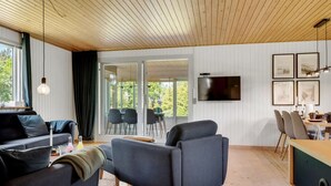 Moderni olohuone, jossa on sohva, nojatuoli, ruokapöytä ja tuoleja.