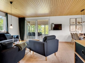 Ein modernes Wohnzimmer mit einer Couch, Sesseln, einem Esstisch und Stühlen.