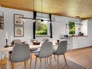 Eine moderne Küche mit Essbereich, Holzbalkendecke und großen Fenstern.