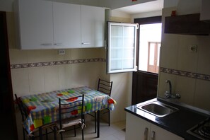 A kitchen with a table, chairs, a window, cabinets, and a sink. - Rustic house featuring traditional Portuguese handicrafts (Nazaré)
