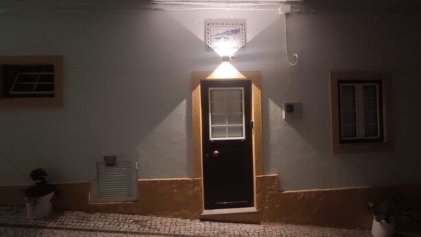 Une entrée d’immeuble avec une porte, une petite fenêtre et un luminaire fixé au mur.