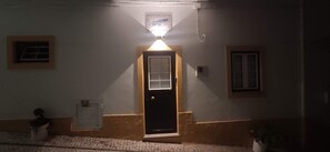 A building entrance with a door, a small window, and a wall-mounted light fixture. - Rustic house featuring traditional Portuguese handicrafts (Nazaré)