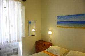 A bedroom with a bed, a dresser, a mirror, and a painting of a beach. - Rustic house featuring traditional Portuguese handicrafts (Nazaré)