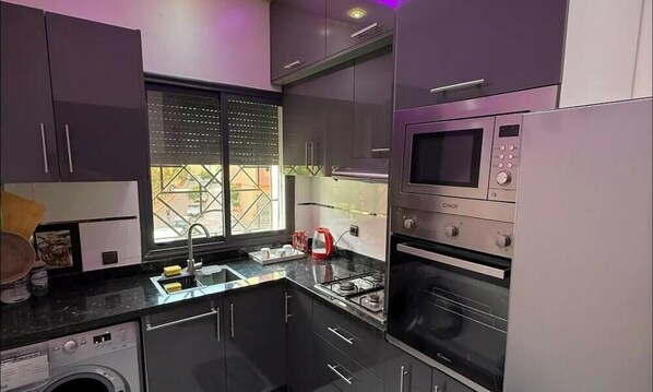Een moderne keuken met een inbouw wasmachine, een magnetron en een kookplaat.