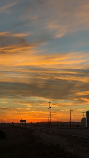 A sunset with a clear sky and a road with a signpost.