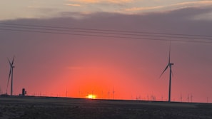 A sunset over a wind farm with multiple wind turbines.