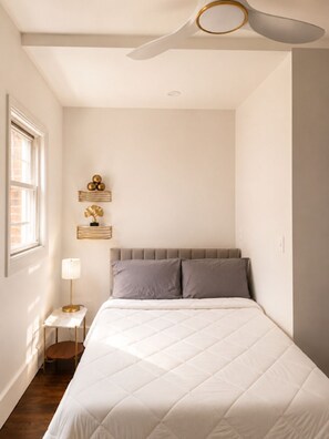 A bedroom with a bed, a nightstand, a lamp, a ceiling fan, and wall decor. - Spacious 3-bedroom apartment on East Jefferson near Downtown (Detroit)