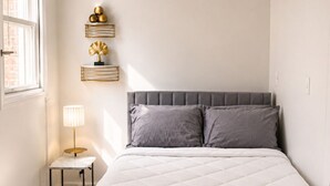 A bedroom with a bed, bedside table, lamp, and decorative items.