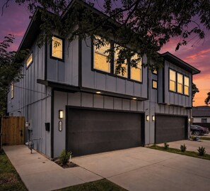Et moderne hus med to etager, garage, velplejet græsplæne og udsigt til vejen.