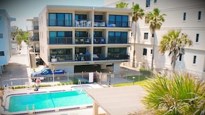 Un hôtel à plusieurs étages doté de balcons, d’une piscine et de palmiers.