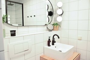 Un bagno con un lavandino bianco, un rubinetto nero e uno specchio con illuminazione.