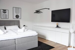 Una camera da letto moderna con un letto, una televisione, un armadio e un portalampada a parete.