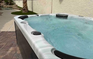 Ein Whirlpool mit strukturierter Außenhaut, einer Bedienkonsole und einer klaren Wasserfläche.