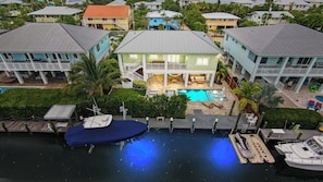 Una casa grande con piscina, barcos amarrados y un muelle.
