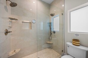 Ein modernes Badezimmer mit einer Duschkabine, einer Toilette und einem kleinen Waschbecken.