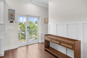 Ein Zimmer mit einem Holzkonsolentisch, einer Schiebetür zum Balkon und einem an der Wand hängenden Bild.