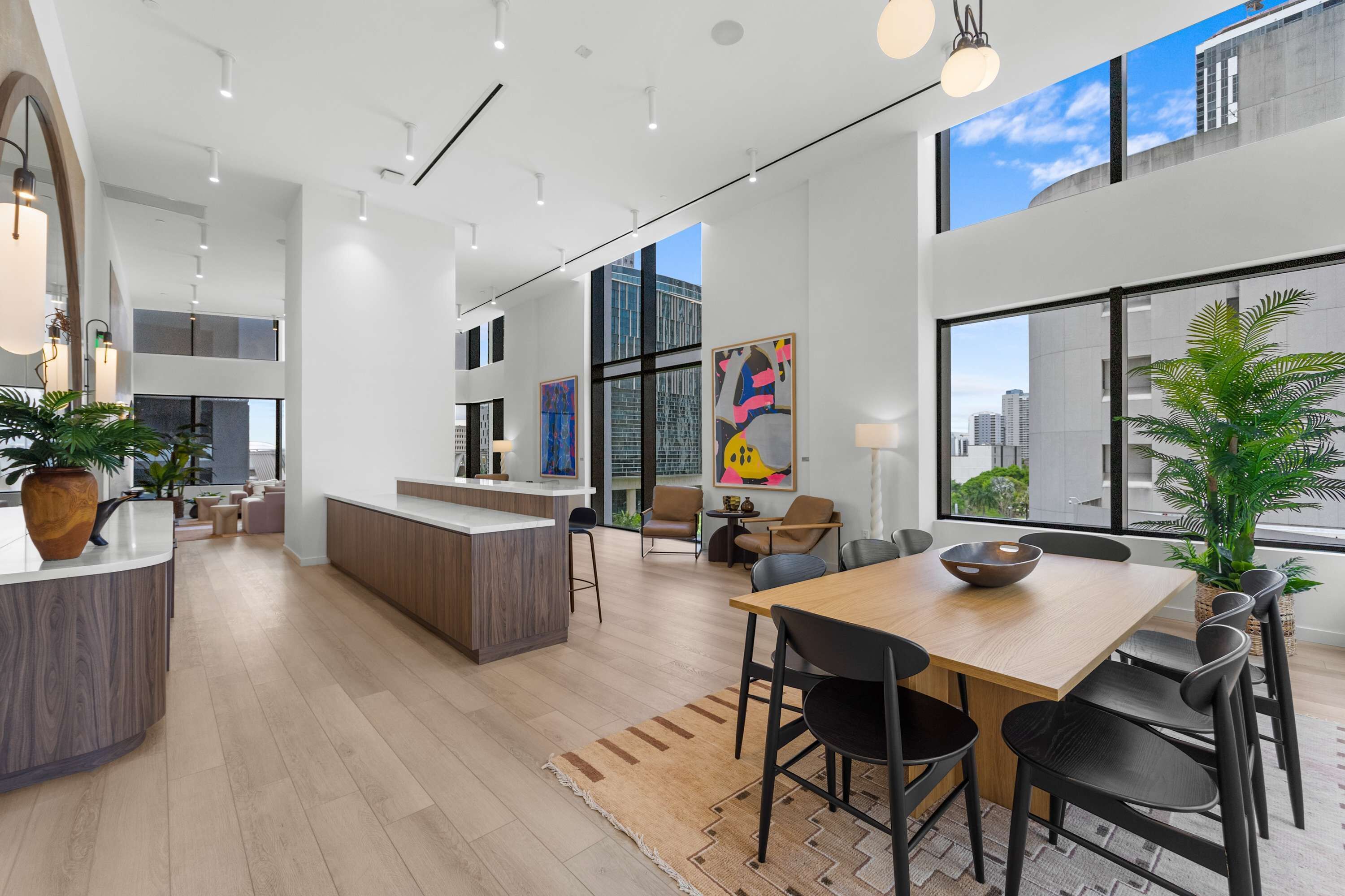 Un intérieur moderne et spacieux comprenant une cuisine, un coin repas et de grandes fenêtres offrant une vue sur la ville.