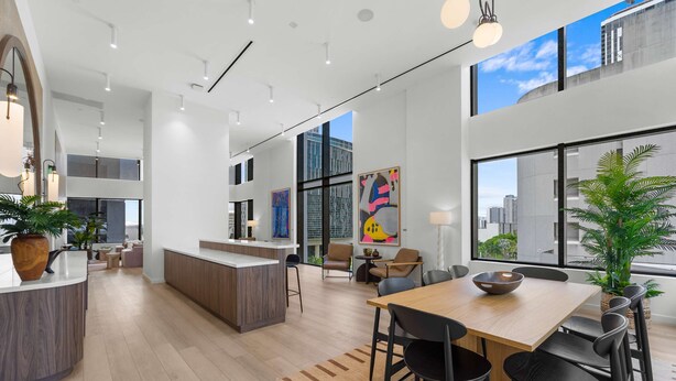 Un interior moderno y espacioso con cocina, comedor y ventanas amplias que ofrecen vistas a la ciudad.
