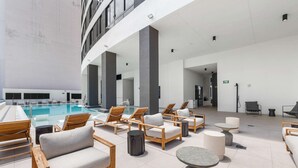 Un área de lounge en la azotea con piscina, sillones y mesas.