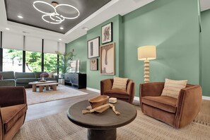 Ein modernes Wohnzimmer mit einer Couch, Sesseln, einem Couchtisch und Kunstwerken an den Wänden.