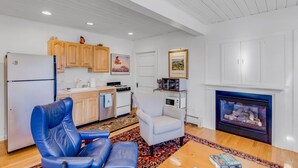 A living room with a fireplace, a kitchen area, and a blue leather chair.