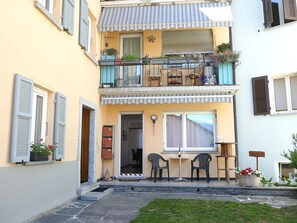 A two-story building with a balcony, a small outdoor seating area, and a door leading to an interior space. - Lodrino Canyoning by Interhome (Lodrino)