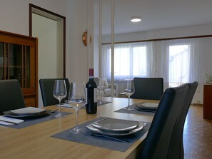 A dining area with a wooden table set for four, including plates, cutlery, and wine glasses. - Lodrino Canyoning by Interhome (Lodrino)