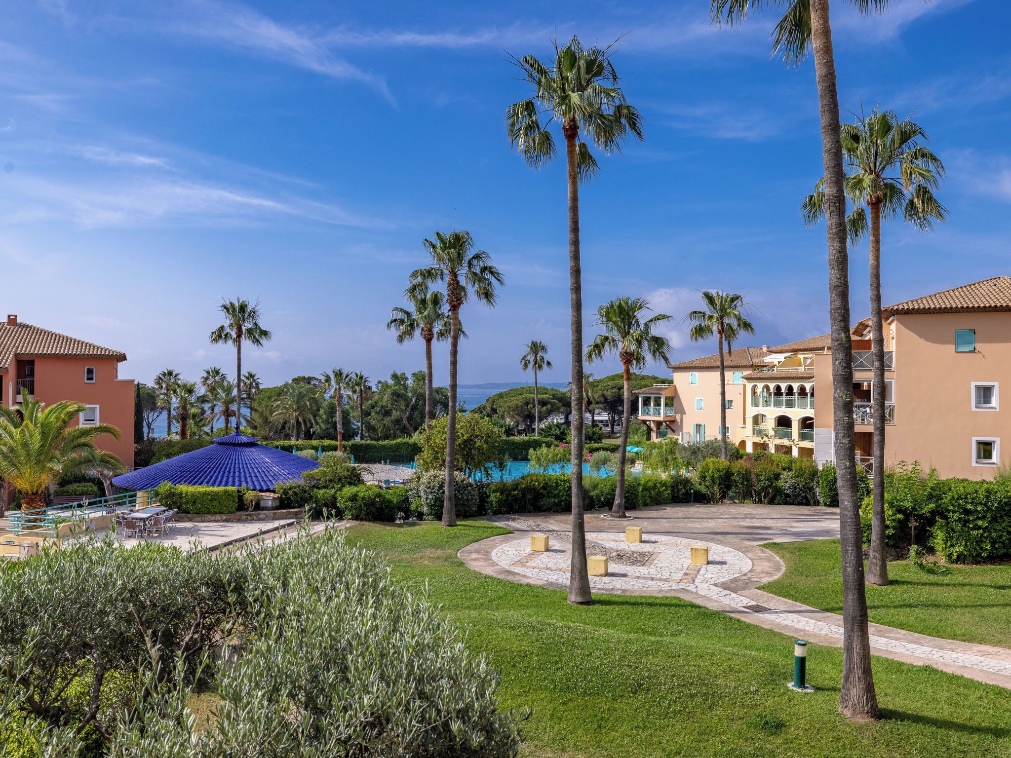 Un resort con palmeras, piscina y edificios de estilo mediterráneo.