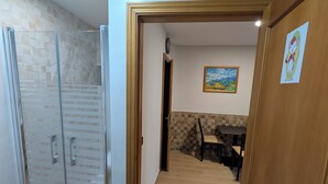 Ein Flur mit einer Duschabtür aus Glas, einer Holztür und einem Essbereich mit Tisch und Stühlen.