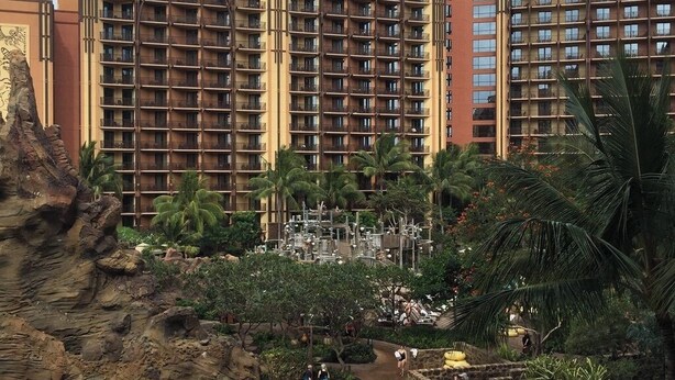 Ein Hotel mit mehreren Stockwerken, einem Poolbereich inklusive Wasserrutschen und Palmen.
