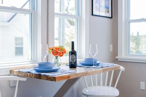 Una mesa de comedor con platos azules, una botella y un jarrón de flores.