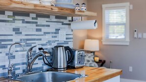 A kitchen with a modern design, featuring a stainless steel sink, a kettle, and a toaster.