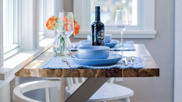 A dining table with blue plates, a bottle, and a glass.