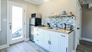 A compact kitchen with a microwave, refrigerator, sink, and a countertop with various items.
