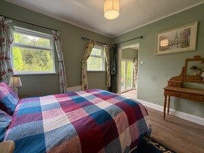 A bedroom with a checkered bedspread, a dresser, a mirror, and a painting on the wall.