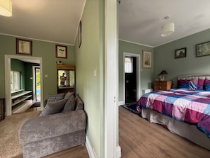 A bedroom with a bed, a window, a door, and a mirror.