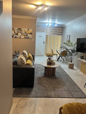 A living room with a sofa, coffee table, TV, and a door leading to another room.
