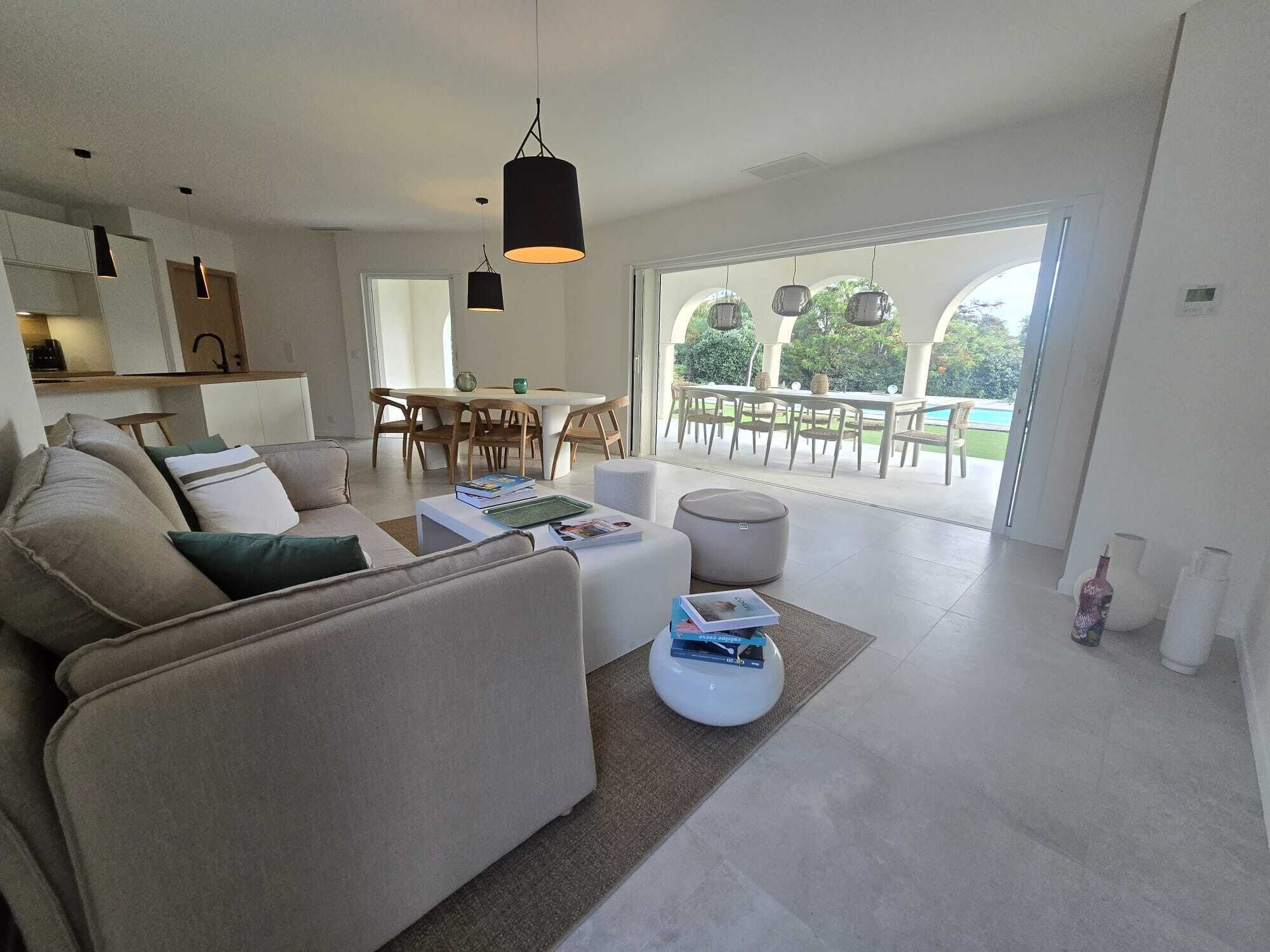 Ein modernes Wohnzimmer mit Sofa, Couchtisch und Essbereich mit Stühlen.