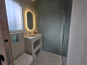 Ein Badezimmer mit Toilette, Waschbecken, Spiegel und Dusche.