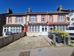 A row of terraced houses with satellite dishes, a driveway, and a parked car.