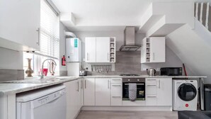 Una cocina moderna con armarios blancos, lavavajillas, lavadora y horno empotrado.