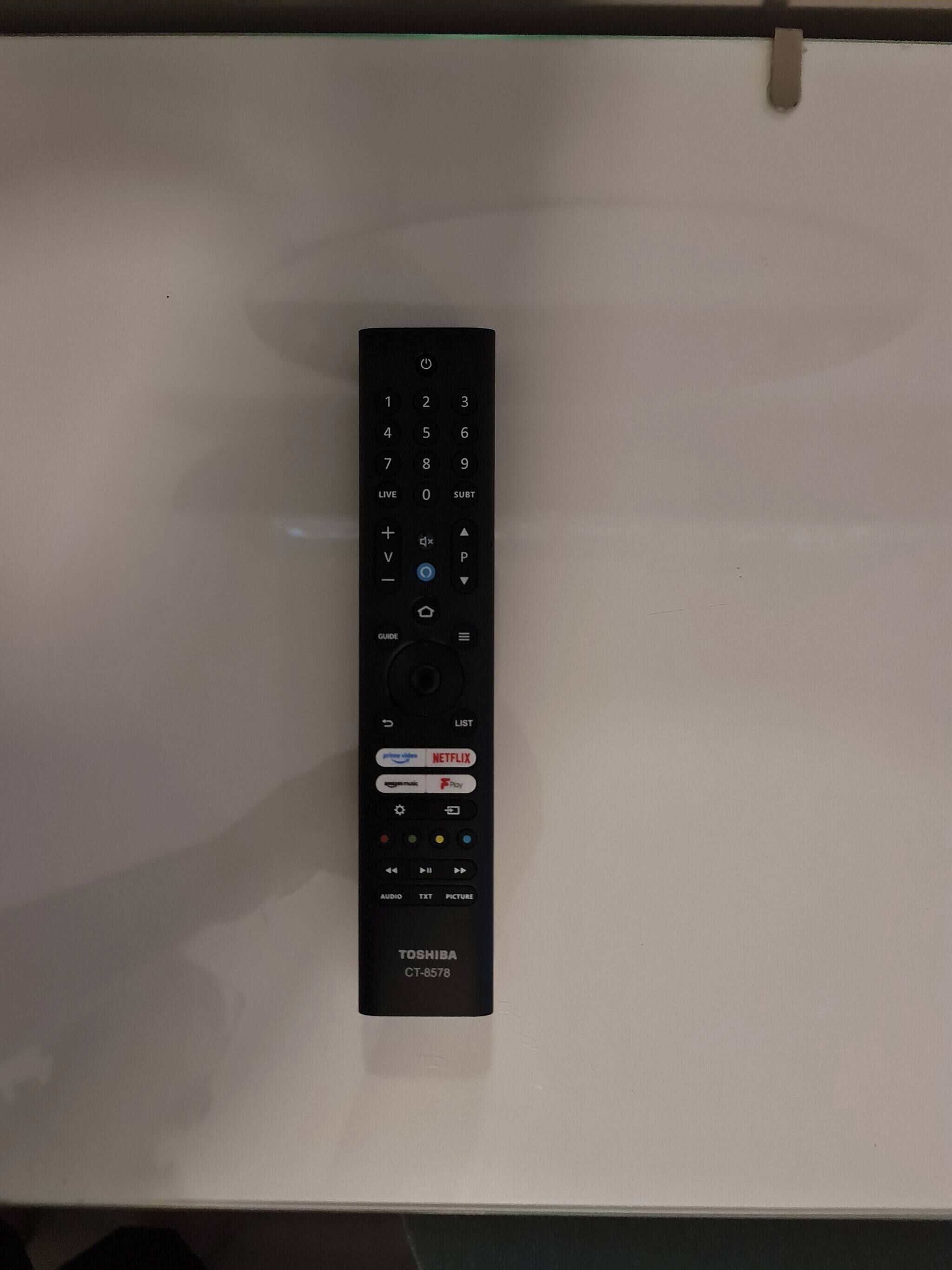 A black remote control with a numeric keypad, directional pad, and various function buttons including volume and power.