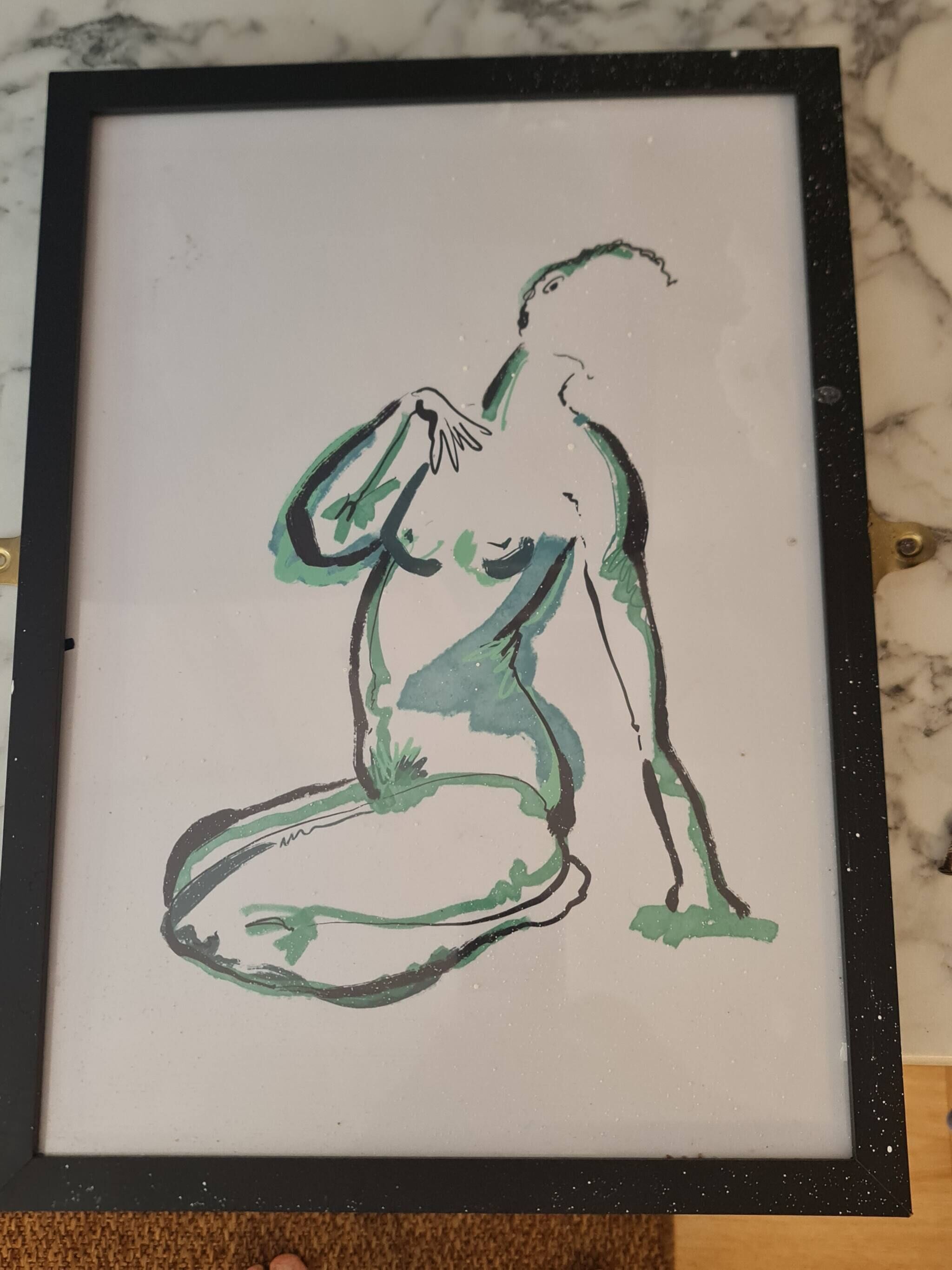 A framed artwork of a figure in a seated pose.