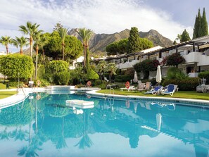 A swimming pool with lounge chairs and a mountain backdrop. - Ca Maestral by Interhome (Marbella)