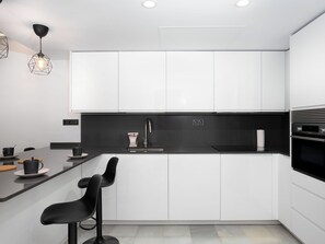 A modern kitchen with white cabinets, a black countertop, and a built-in oven. - Ca Maestral by Interhome (Marbella)