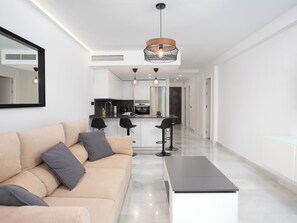 Uma sala de estar moderna com um sofá, mesa de centro e dois bancos altos.