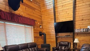 Ein Holzinnenraum mit Kamin, Ledersofas und einem aufgehängten Hirschkopf.