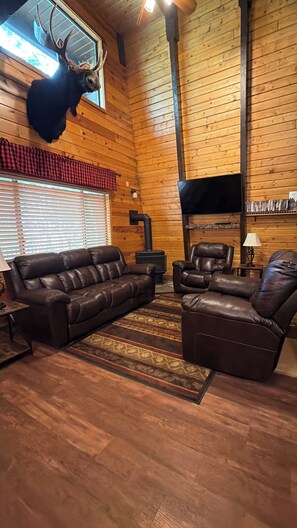 A wooden interior with a fireplace, leather sofas, and a mounted deer head. - 20 min from Yellowstone NP, hot tub, sleeps 18, 3-bedroom, 2.5 bath, Island Park (Island Park)