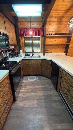 A kitchen with wooden cabinets, a microwave, a sink, and a window with blinds. - 20 min from Yellowstone NP, hot tub, sleeps 18, 3-bedroom, 2.5 bath, Island Park (Island Park)