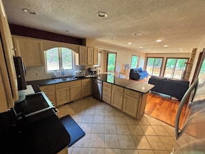 A kitchen with a central island, a dining area with a blue sofa, and large windows.